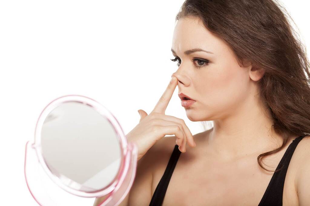 Aynada burnunu inceleyen bir kadın fotğrafı